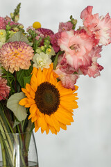 Vibrant floral bouquet with sunflower and gladiolus in a clear vase
