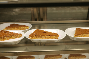 Slices of rich caramel cake on display in a bakery case