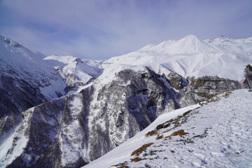 A snow-covered mountain range in the Caucasus region near the Gudauri ski resort. Georgia. Snow-capped mountain peaks and steep slopes.