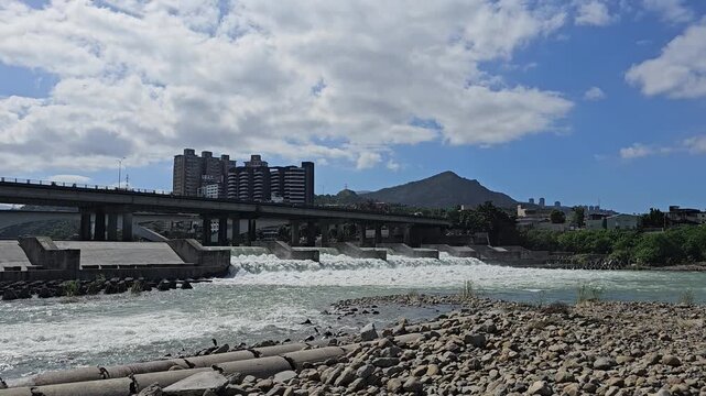 Taipei City, Taiwan. November 15, 2025. Xindian River weir with distant mountains and urban riverside landscape creating a balanced eco scene of nature and city