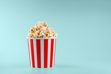Classic red striped popcorn cardboard cup on blue background