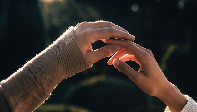 Two hands gently touching in soft golden sunlight conveying connection and tenderness