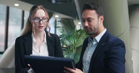 Experienced businessman gives feedback to a fresh female employee on documents while pointing out mistakes and discussing improvements in a supportive way in a modern office - Powered by Adobe