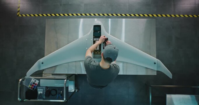Technician Servicing Large Surveillance Drone. Man Performing Maintenance or Integrating Systems Into Large Aerial Drone. Concept Meticulous Process of UAV Servicing and Quality Control. Top View.