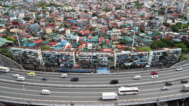 High angle drone view of the San Andres and Paco districts in Manila, Philippines. A busy elevated expressway with cars and buses curves across the foreground.