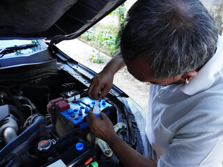 Mechanic or Owner Checking and Filling Car Battery Water Level for Maintenance.