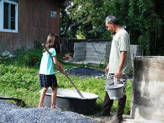 Father and Daughter Mixing Cement or Concrete for Home Construction Project.