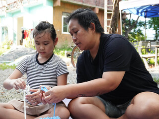 Mother and Daughter Learning to Knit or Crochet Together Outdoors.