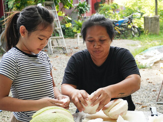 Mother and Daughter Peeling Pomelo Fruit Together Outdoors, Food Preparation.