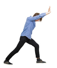 Side view young male student pushing hard with both arms outstretched and palms up against an invisible barrier. Full body length angled forward to exert maximum force. Effort on overcoming challenges