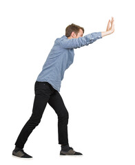 Side view young male student pushing hard with both arms outstretched and palms up against an...