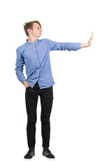 Young male student standing full length, looking aside as keeps his right arm straight out with his palm facing out in a clear stop or halt gesture and other hand is casually resting in his pocket