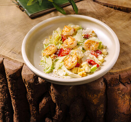 Fresh shrimp salad with greens and tomatoes on a wooden table