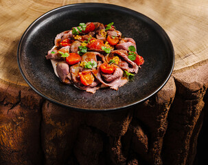 Sliced roast beef with tomatoes served on a rustic wooden table