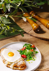 Delicious brunch plate with croissant, egg, and fresh salad at rustic setting