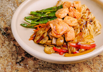 Salmon with noodles and vegetables served in a round bowl