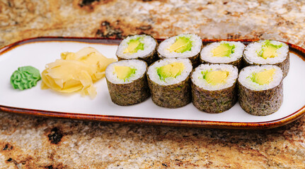 Fresh avocado sushi rolls served on a white plate with ginger and wasabi