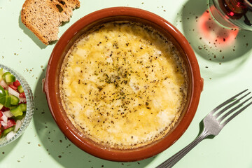 Grilled provolone cheese seasoned with oregano on green background.
