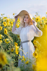 Beautiful blonde girl in a white dress in a field of sunflowers