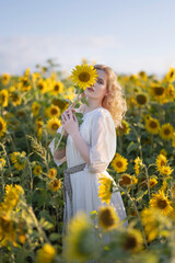 Beautiful blonde girl in a white dress in a field of sunflowers