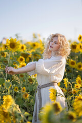 Beautiful blonde girl in a white dress in a field of sunflowers
