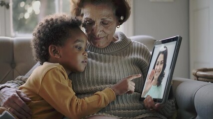 Grandmother and young child engaging in a video call on a tablet, pointing at the screen for intergenerational connection concept and remote communication