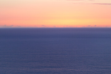 Obraz premium Sea horizon at sunset, with warm color gradients in the sky and calm water. Minimalist and soothing seascape.