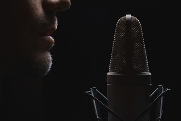 Studio close-up. Voice test into grid mic. Mood light, dark art. Sound, talk, rec cue.