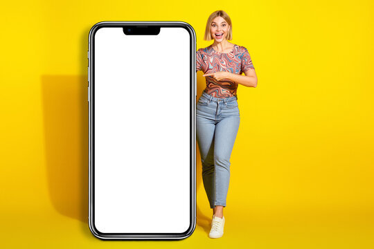 Young stylish woman in casual attire presenting a blank board against a vibrant yellow backdrop, ready for your text