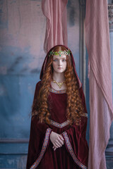 A girl in an elf costume in a studio with fabrics. Medieval decorations