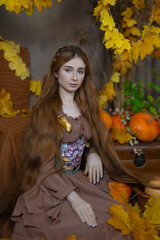Long-haired girl in a studio among leaves and pumpkins