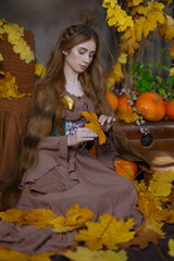 Long-haired girl in a studio among leaves and pumpkins