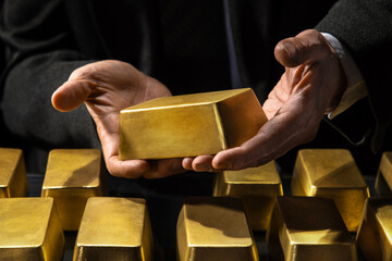 Hands of a banker or businessman, bank vault manager holding a gold bar, gold holdings concept....
