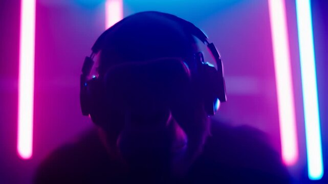Silhouette of person wearing VR headset and headphones in neon light