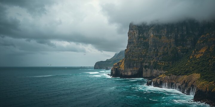A large cliff overlooking a blue ocean on a gloomy day, emphasizing erosion risk and natural landscape preservation
