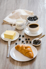 Breakfast with croissant, milk, butter, huckleberry jam and coffee
