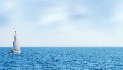 Sailboat cruising calm blue sea under sky