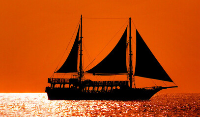 Majestic sailing ship navigating golden sunset waters