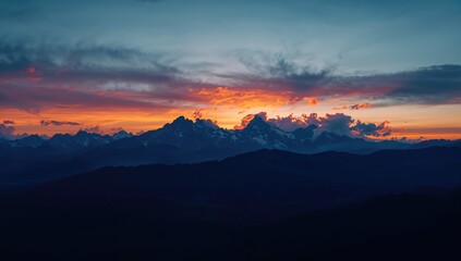 Fototapeta premium Mountain landscape with vibrant sunset and cloudy sky, suitable as a background for outdoor travel content