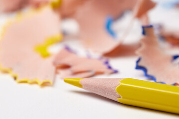 yellow pencil tip surrounded by colorful wood shavings on a white background