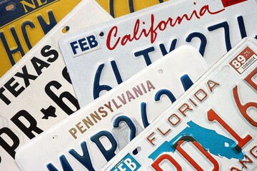 Old US car license plates with various state names close up. Concept of driving in United States. Reaching a car registration