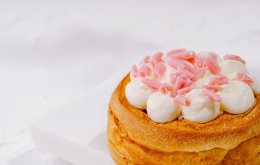 Delicious pastry topped with cream and pink sprinkles on a white plate