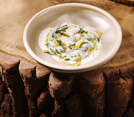 Fresh homemade ravioli served on a rustic wooden table with creamy sauce