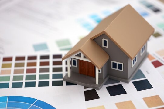 Small toy house and papers with color palette samples. Concept of interior and exterior design and painting. Color spectre for choosing tone