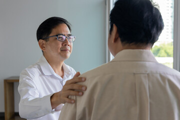 Asian businessman putting his hand on this colleague&rsquo;s shoulder for encouragement and support