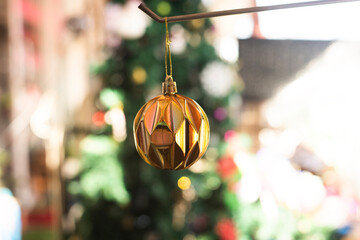 Shiny Gold Christmas Ornament with Wavy Texture Against Bright Colorful Bokeh