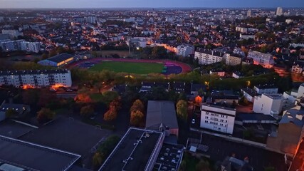 Soft night lights highlight rooftops and streets in a quiet Rennes neighborhood of Maurepas beneath a dark sky, approach to Track