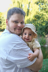 Fototapeta premium Father Holding Smiling Baby in Park Portrait