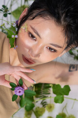 The woman in a dynamic pose, arching her back while surrounded by greenery and flowers.