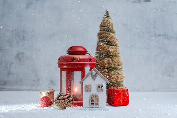 Festive Christmas scene with red lantern with a glowing light, miniature house, gifts and a decorative Christmas tree with snow. Winter composition for seasonal greeting cards and New Year.